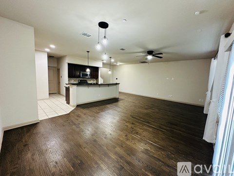 A spacious kitchen and living room with wooden floors and white walls.