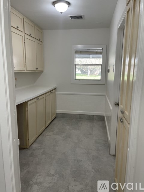 A kitchen with white cabinets and a window.