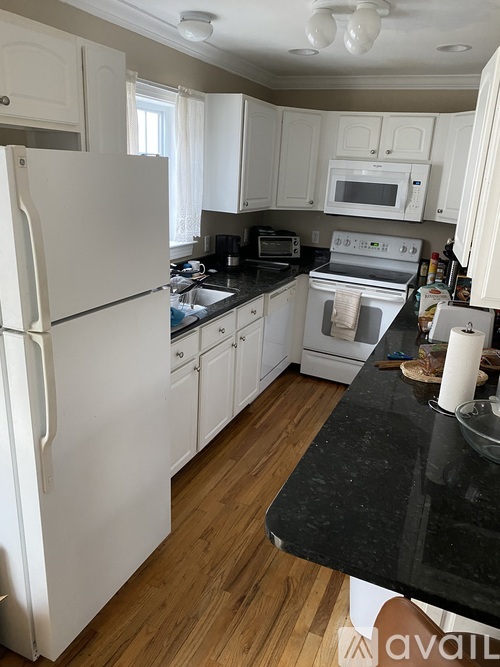 A kitchen with white appliances and wooden floors.