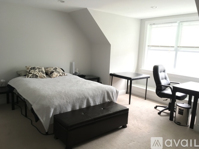 A bedroom with a bed, nightstand, and window.