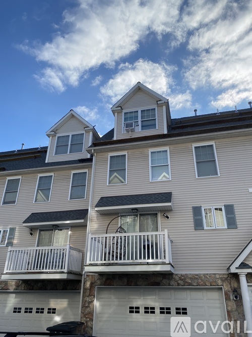 A two-story building with a balcony and a garage door.