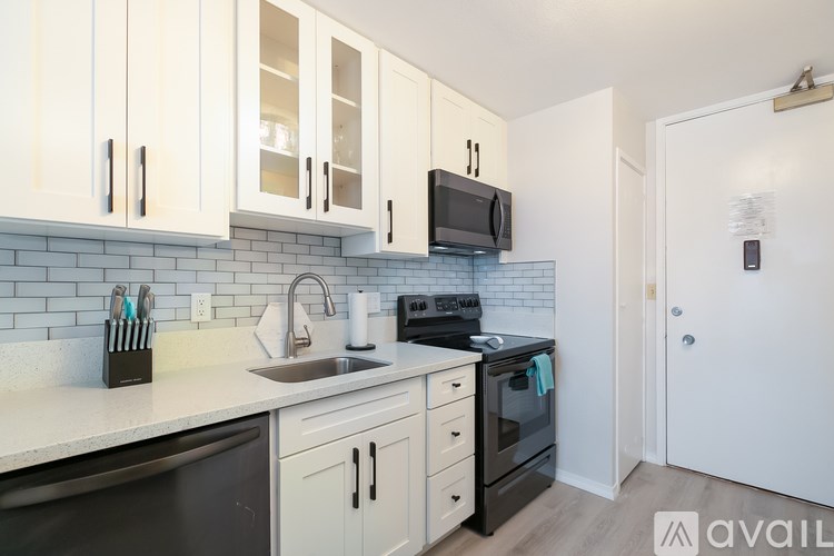 A kitchen with white cabinets and black appliances.
