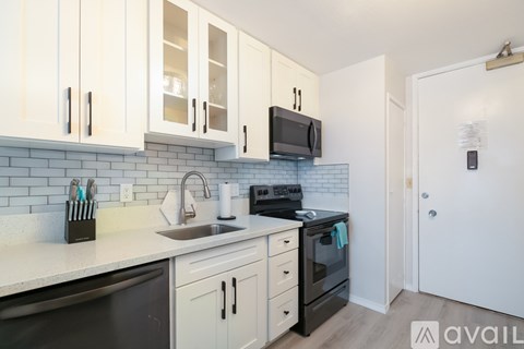 A kitchen with white cabinets and black appliances.