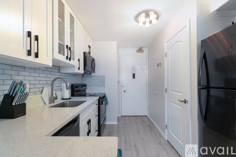 A kitchen with white cabinets and a black refrigerator.