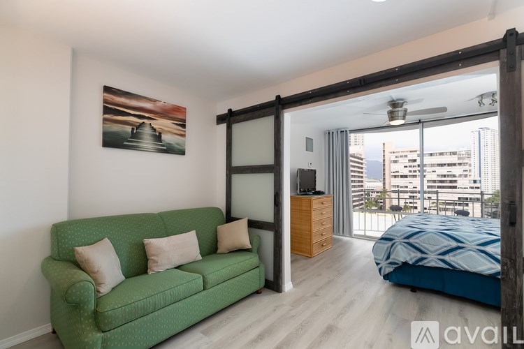 A room with a green couch and a bed with a blue comforter.