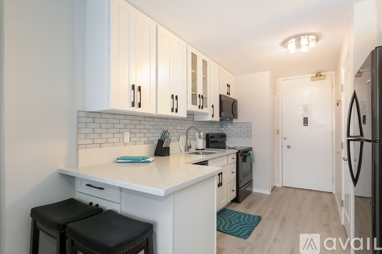 A kitchen with white cabinets and a black fridge.