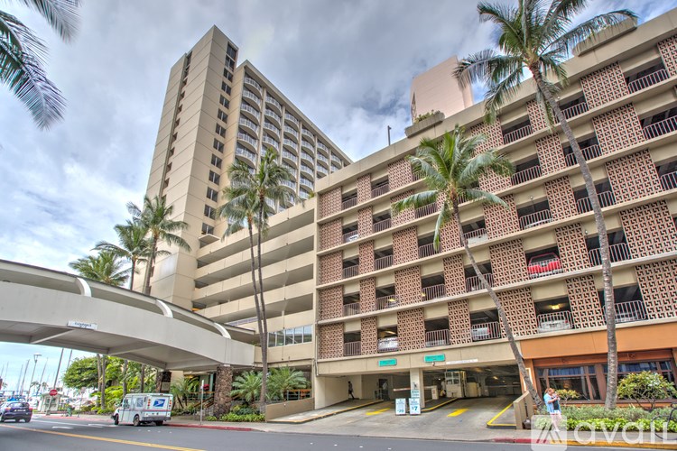 A tall building with a parking garage in front of it.