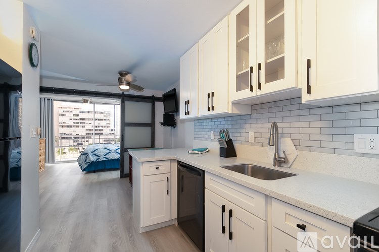 A kitchen with white cabinets and a blue bed in the background.