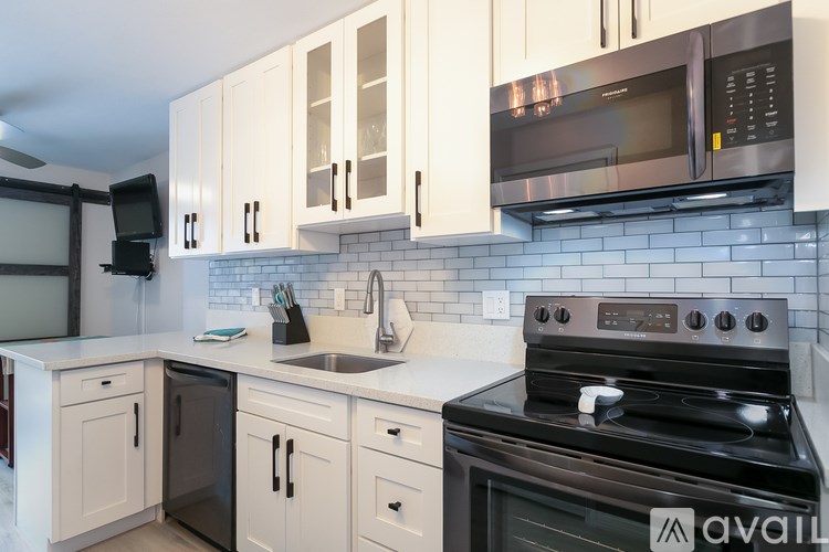 A kitchen with white cabinets and a black stove top oven.