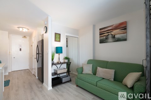 A living room with a green couch and a painting on the wall.