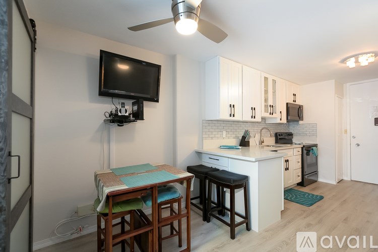 A kitchen with a table and chairs and a television on the wall.