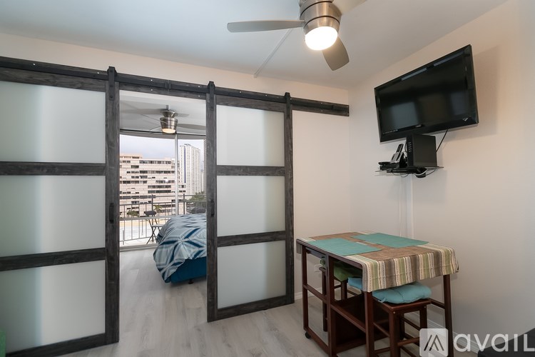 A room with a sliding door, a table with a striped tablecloth, and a television mounted on the wall.