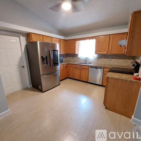 A kitchen with wooden cabinets and a stainless steel refrigerator.