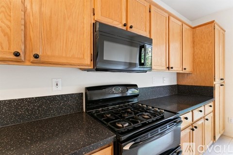 A kitchen with wooden cabinets and a black microwave above the stove.