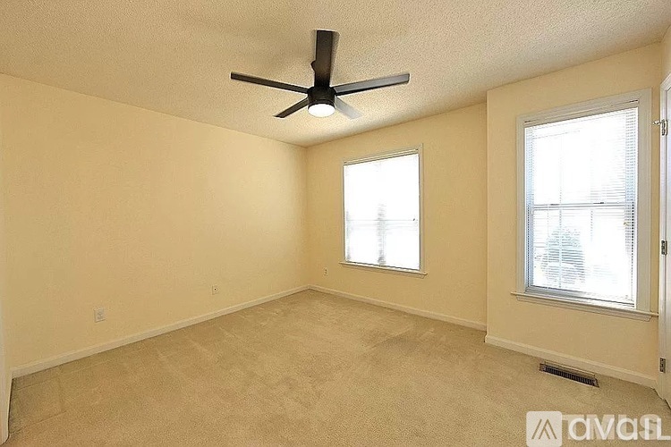 A room with a ceiling fan and two windows.