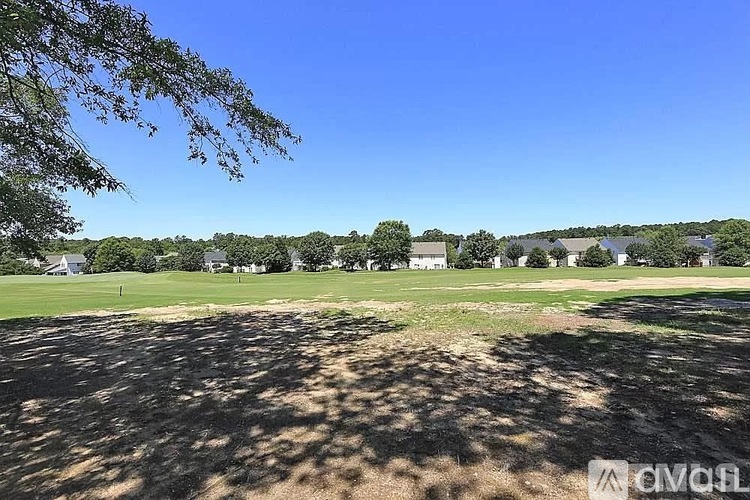 A golf course with a clear blue sky and trees in the distance.