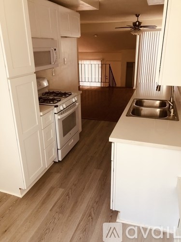 A kitchen with white appliances and wooden floors.