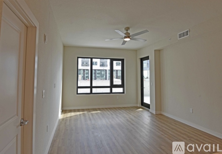 A spacious room with a ceiling fan and large windows.