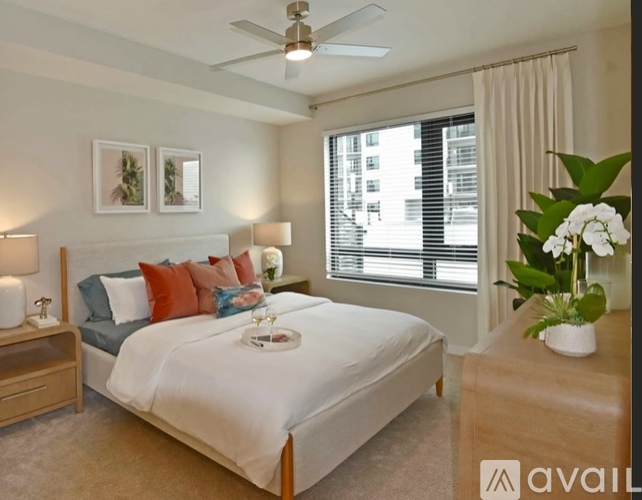A bedroom with a large bed, a ceiling fan, and a window with blinds.