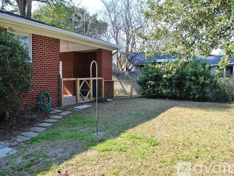 A backyard with a brick building and a green hose.