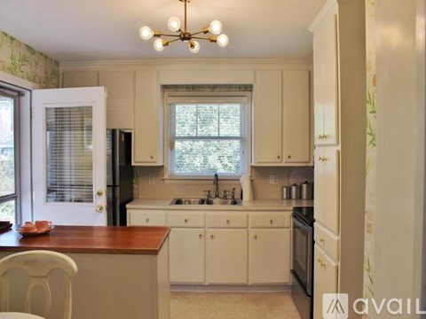 A kitchen with white cabinets and a wooden island.
