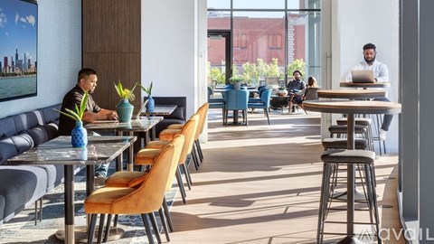 A man is sitting at a table in a restaurant with a laptop open in front of him.