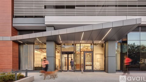 A modern building with a glass entrance and a dog walking in front.