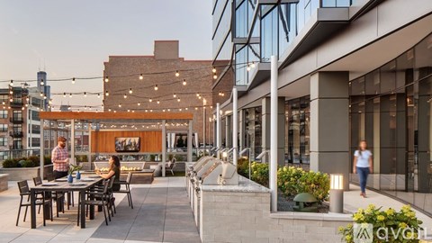 A modern outdoor seating area with people dining and a building in the background.