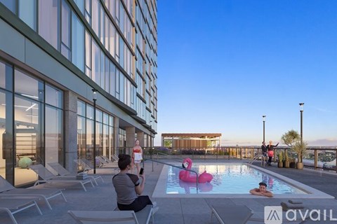 A man is sitting on a chair on a patio with a pool and a pink flamingo float in the pool.