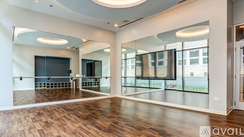 A spacious room with wooden floors and large mirrors on the walls.