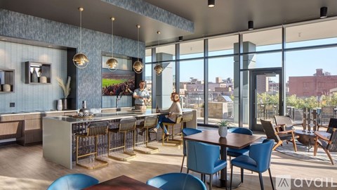 A modern kitchen and dining area with blue chairs and a view of the city.