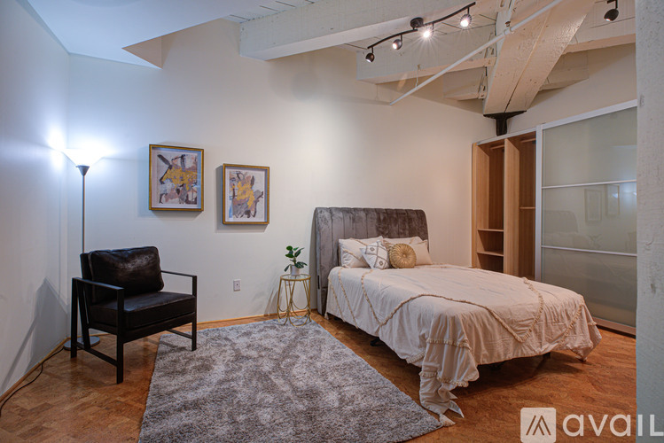 A bedroom with a bed, chair, and artwork.