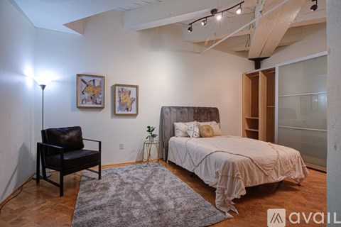 A bedroom with a bed, chair, and artwork.