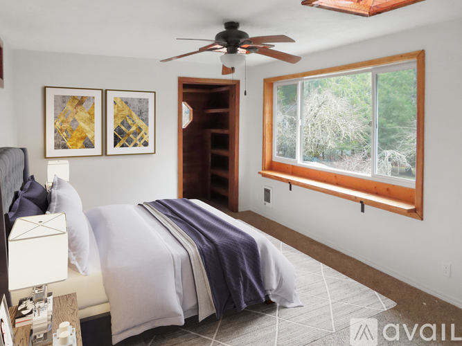 A bedroom with a bed, a ceiling fan, and two pictures on the wall.