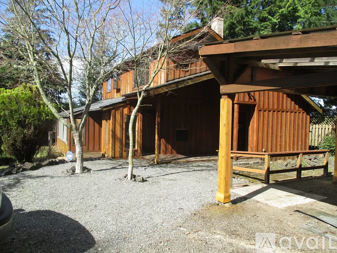 A wooden house with a porch and a tree in front.