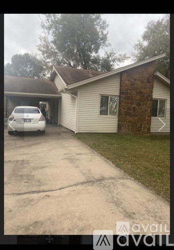 A car is parked in front of a house with a stone pillar.