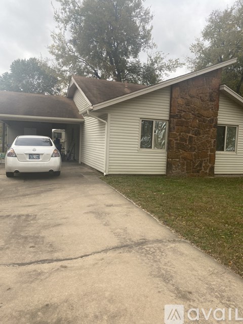A car is parked in front of a house with a stone pillar.