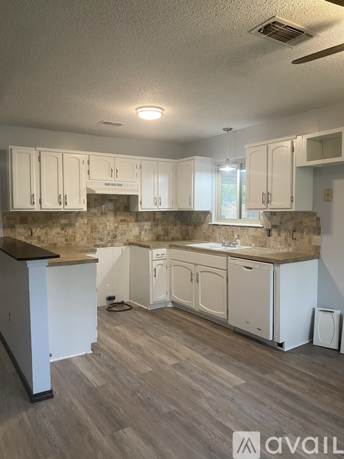 A kitchen with white cabinets and a wooden island.