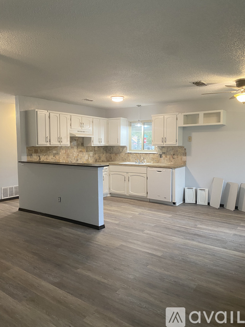 A kitchen with white cabinets and a stone backsplash is available for rent.