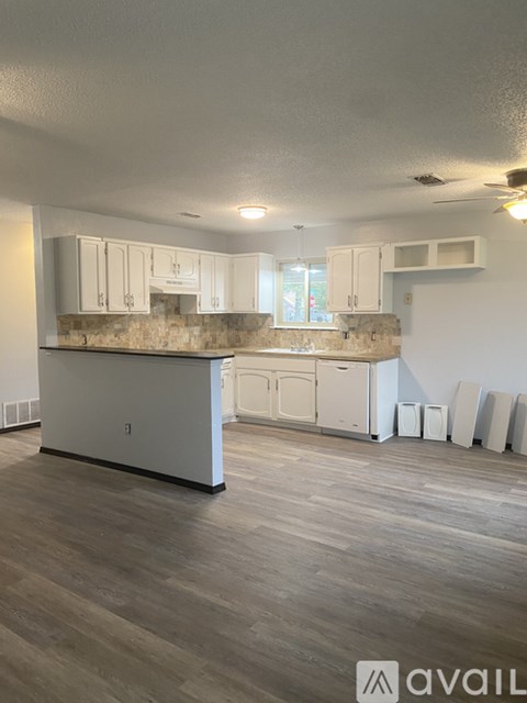 A kitchen with white cabinets and a stone backsplash is available for rent.