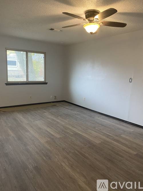 A room with a ceiling fan and wooden flooring.