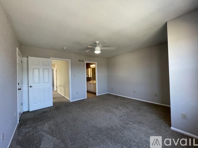 A spacious room with a carpeted floor and a ceiling fan.