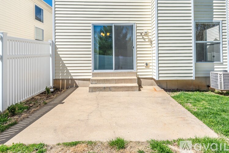 A house with a white fence and a concrete walkway leading to the front door.