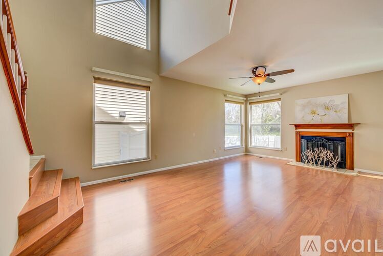 A spacious living room with a fireplace and a staircase on the left side.