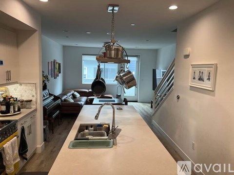 A modern kitchen with a long counter and a hanging pot rack.