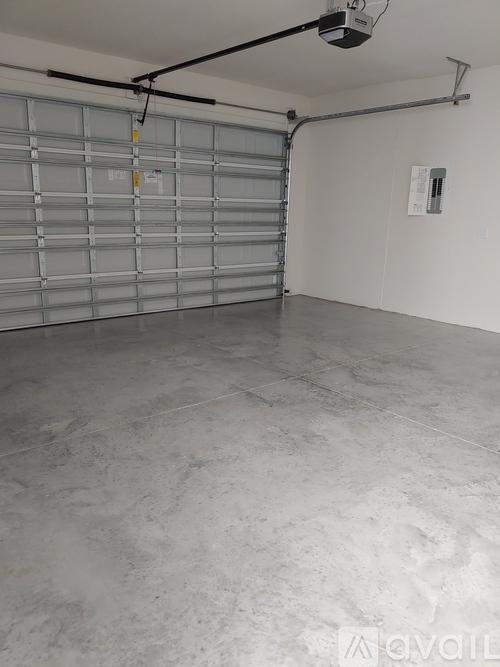 A spacious garage with a closed metal door and a concrete floor.