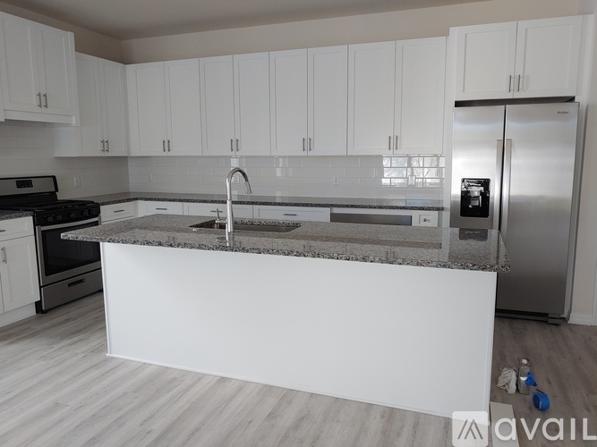 A kitchen with white cabinets and a marble countertop.