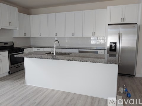 A kitchen with white cabinets and a marble countertop.