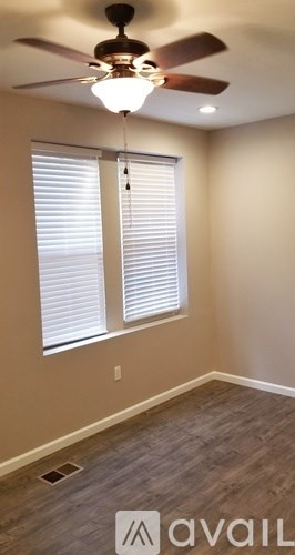 A room with a ceiling fan and a window with blinds.