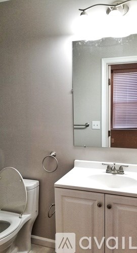 A bathroom with a toilet, sink, and mirror.